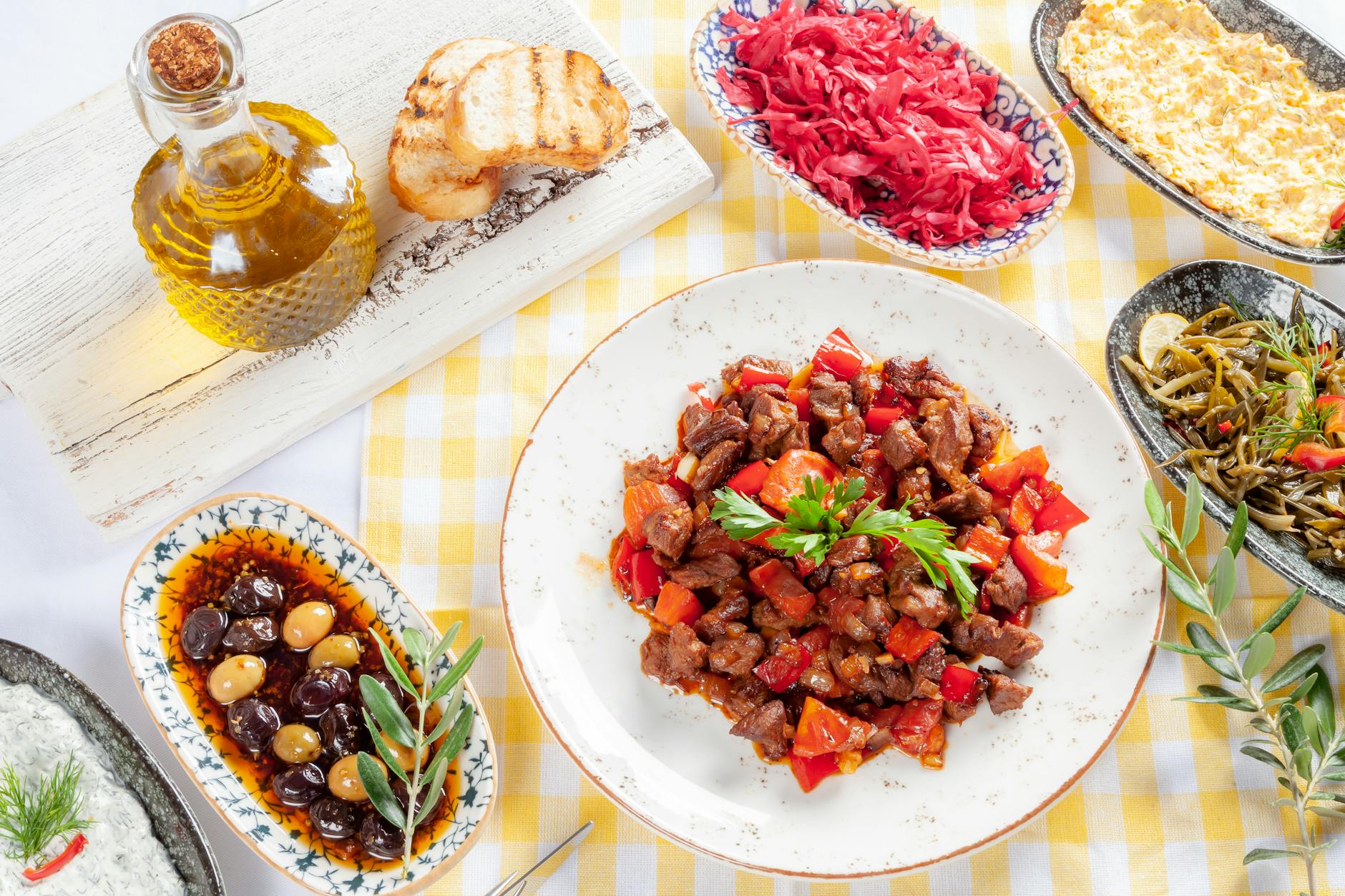 Mesa luminosa con bol mediterraneo de legumbres, verduras asadas, aceite de oliva y pan integral.